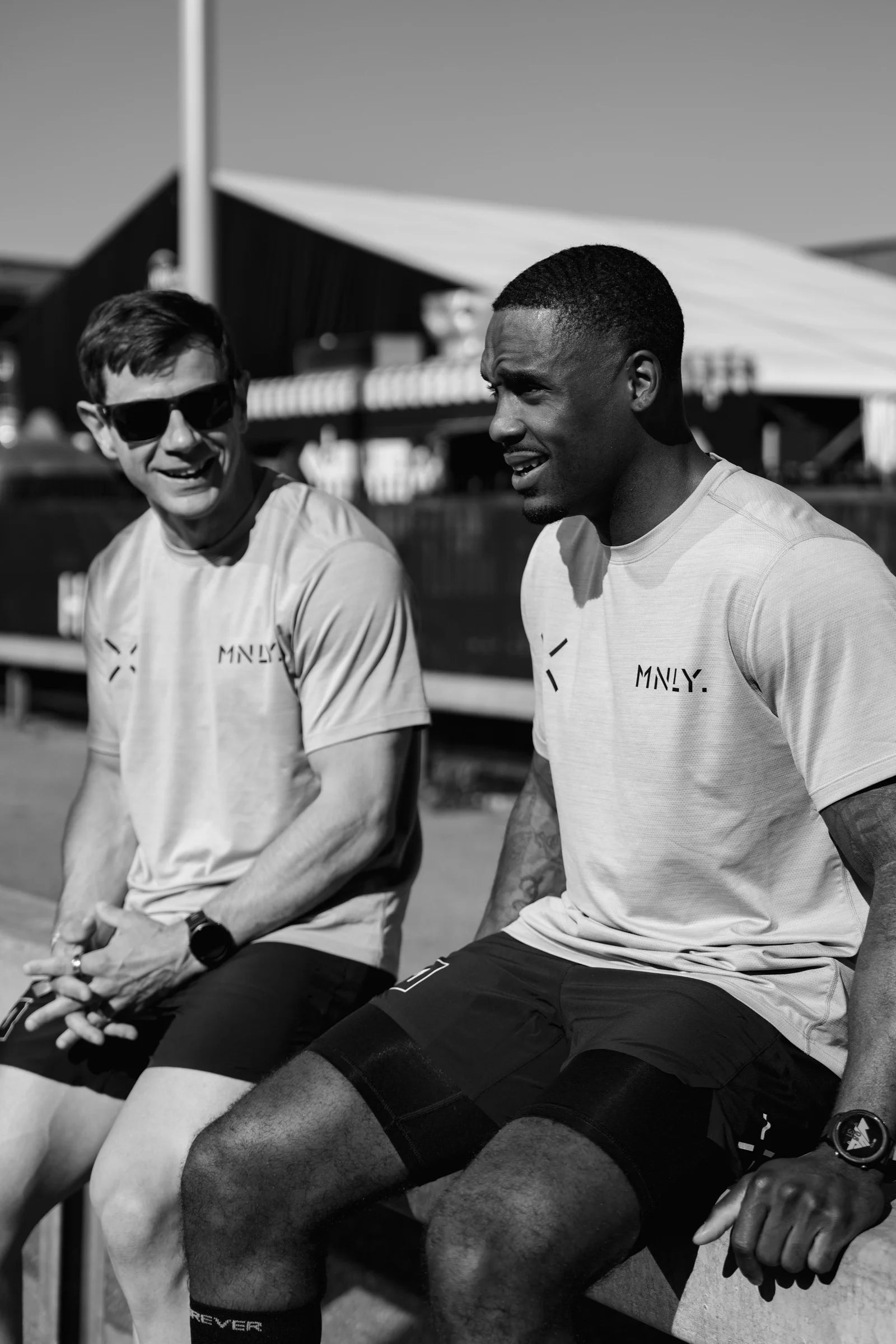 Two athletes in MNLY shirts sitting together at a competition