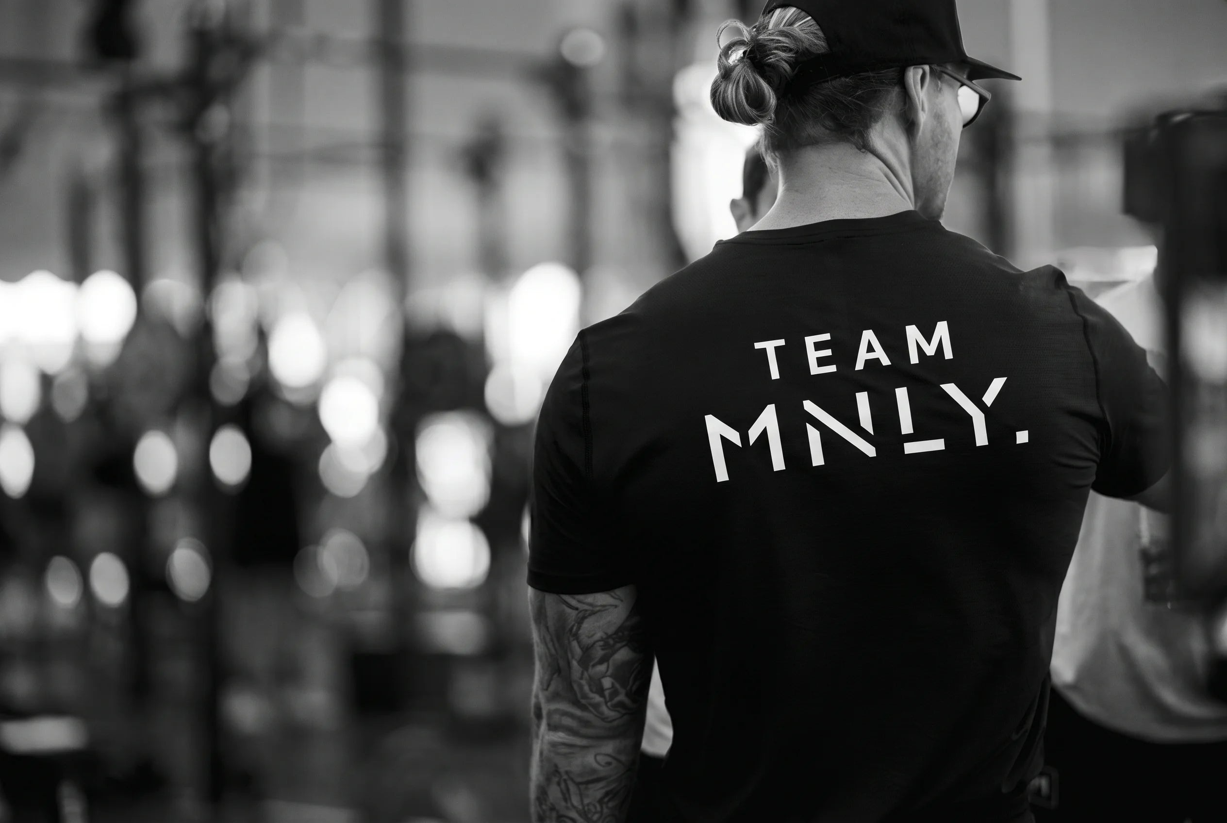 An athlete from behind wearing a Team MNLY shirt in a gym
