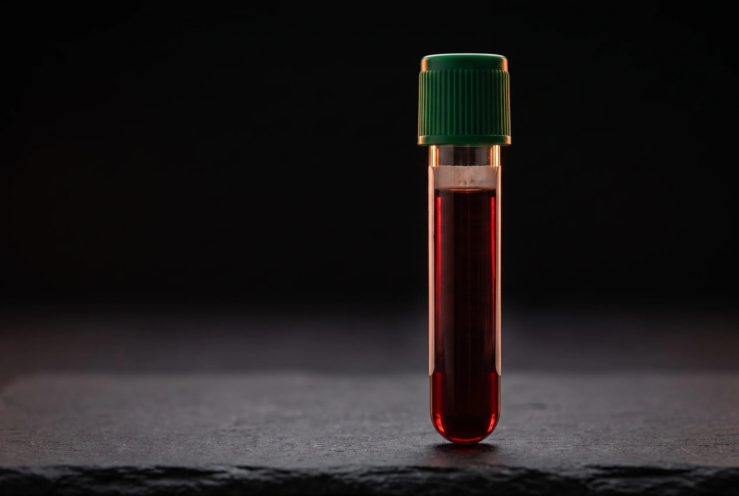 A filled blood collection vial standing on dark slate